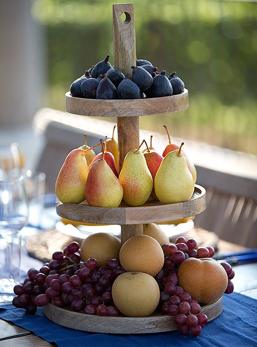 A tiered stand piled high with seasonal fruit pulls double-duty as decor and serving piece.
