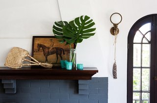 Lizzie keeps it low-key on the mantel with a jockey print from a Claremont, CA, antiques shop and palm fronds snipped from the yard.
