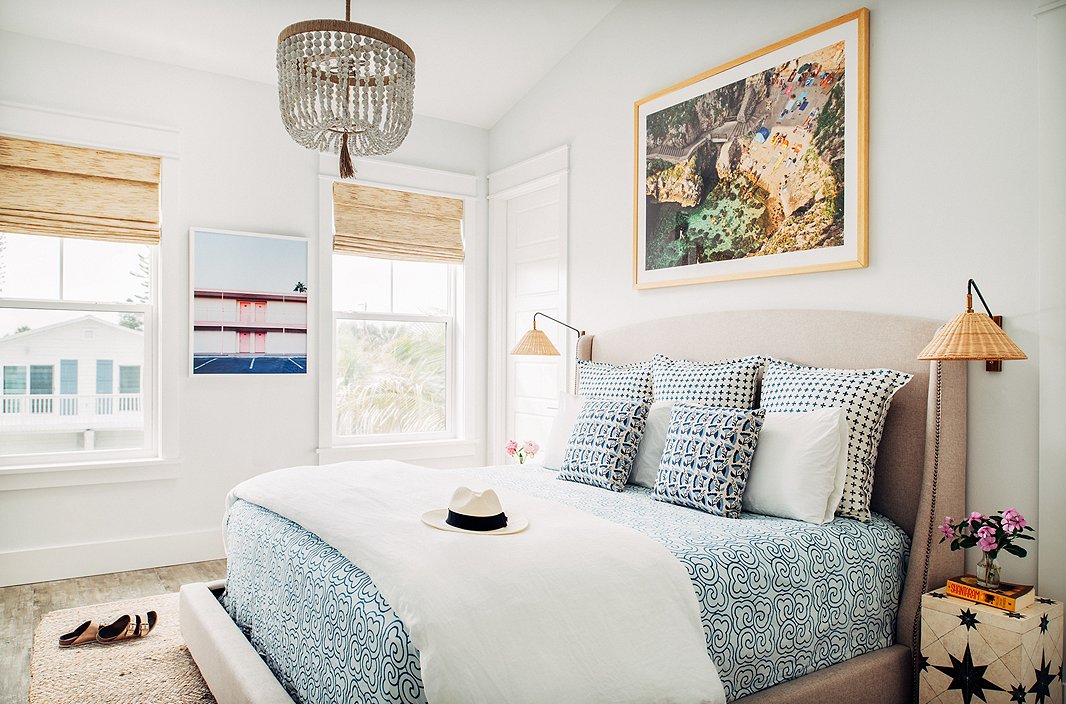 “I love mixing patterns and textures and prints,” Hannah says—and she does so fearlessly, whether it’s a bright banana-leaf fabric paired with a bold striped rug or a mix of three geometric prints on a bed, as in this master bedroom. “I am of the mindset that if you love something, it will somehow work into the space.” For a similar chandelier, see the Surrey. The art on the far wall is Vegas Motel by Claudia Lucia.
