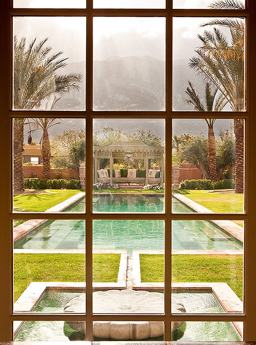 A window perfectly frames the courtyardlike garden and pool area. 
