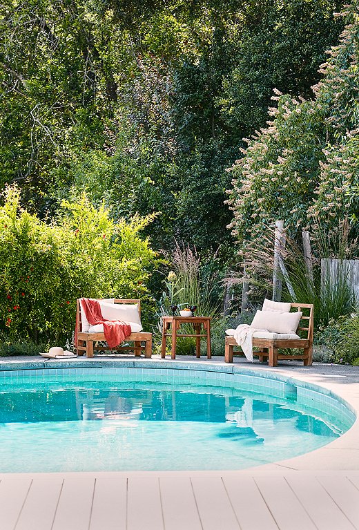 Weathered wood furnishings play up the wildness of the poolside landscaping. Photo by Laura Resen.
