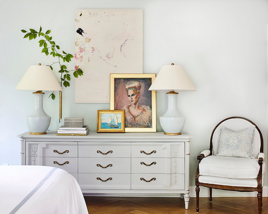 Painted in a soft shade of gray, the dresser nearly disappears against the bedroom wall. The large abstract artwork is by Molly Ledbetter, the portrait is by Minnette’s maternal grandmother, and the nautical scene is by Sam Barber, a family friend.
