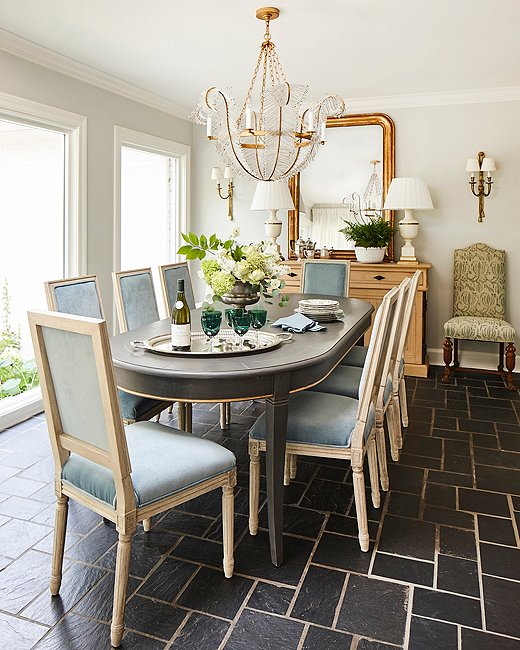 Floor-to-ceiling windows along one wall of the dining room help to bring the outdoors in. A Visual Comfort chandelier adds a touch of glamour and anchors the French Directoire-style table below.
