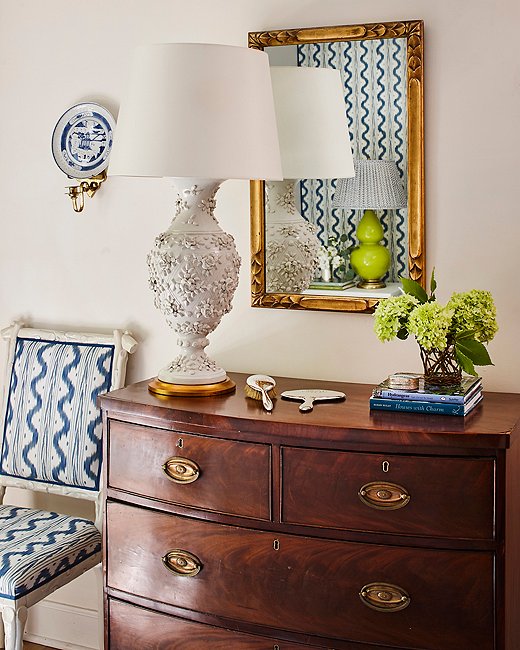 A mirror handed down from Minnette’s grandmother reflects the lively pattern on the opposite wall. The chest belonged to the designer’s in-laws, and the lamp was an online auction score. “We are lucky to have inherited several nice pieces from both of our families, and I am always collecting things I find pretty or interesting,” Minnette says.
