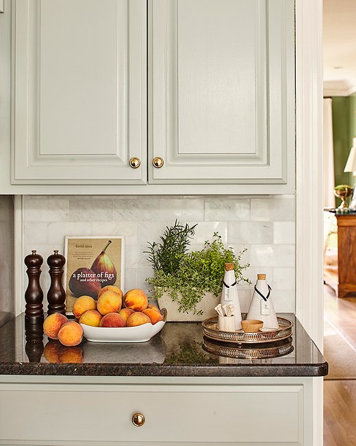 A new marble-tile backsplash lends a subtle hint of luxe texture to the kitchen. Minnette replaced the existing hardware with unlacquered brass knobs. “I like how the finish changes over time,” she says.
