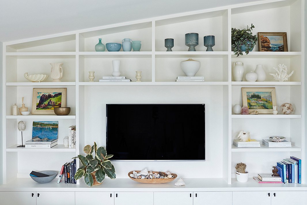 Minnie added a wall of built-ins during the renovation process. To pull attention away from the TV, the One Kings Lane design team styled the shelves with a mix of new and vintage pieces, including coral and raw-wood accents and pottery in ocean hues. “It softens the whole idea of a television,” Minnie says. “It’s made it into this really lovely space to look at.”
