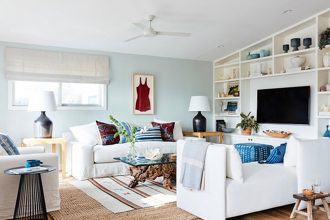 Minnie’s checklist for the living room seating: streamlined, white, slipcovered (see: sand), and deep enough to curl up on. “I always feel like you want to be able to tuck your legs under you without your knees falling off the edge of the sofa,” she says. “To me that’s the mark of a great, comfortable family-living-space sofa.” The striped rug and the bathing-suit artwork are vintage, the table lamps are by Ralph Lauren Home, and the window treatments are by The Shade Store.
