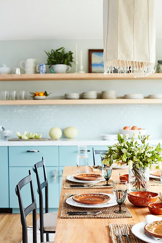 Minnie’s terracotta plates provide a warm contrast to the cool blue surroundings, while woven place mats and a fringed fabric light fixture add organic allure.

