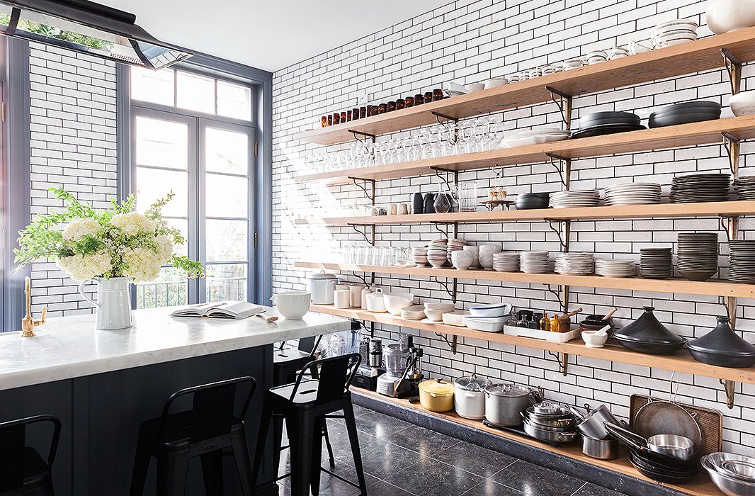 Appliances stay accessible along the bottom of the wall of custom shelving. With five kids and frequent dinner parties, plates are “always breaking, chipping, peeling. But that’s what makes it fun.”
