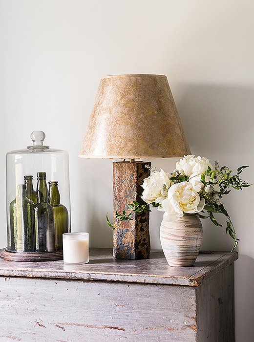 A collection of green glass vases is one of the only pops of color in the serene guest bedroom.
