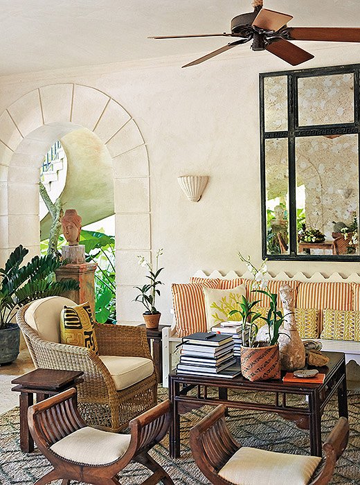 “Rooms become relaxed when there is a little patina on the furniture and textiles are mixed in a casual way,” notes Bunny in her book. She brings that sun-washed feel to another seating area, where faintly weathered woods mingle with fabrics in golden and coral notes that pay homage to the island locale.
