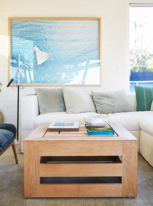 In the tennis house, a watery photograph nods to the Pacific views outside, while a teak coffee table adds natural warmth.
