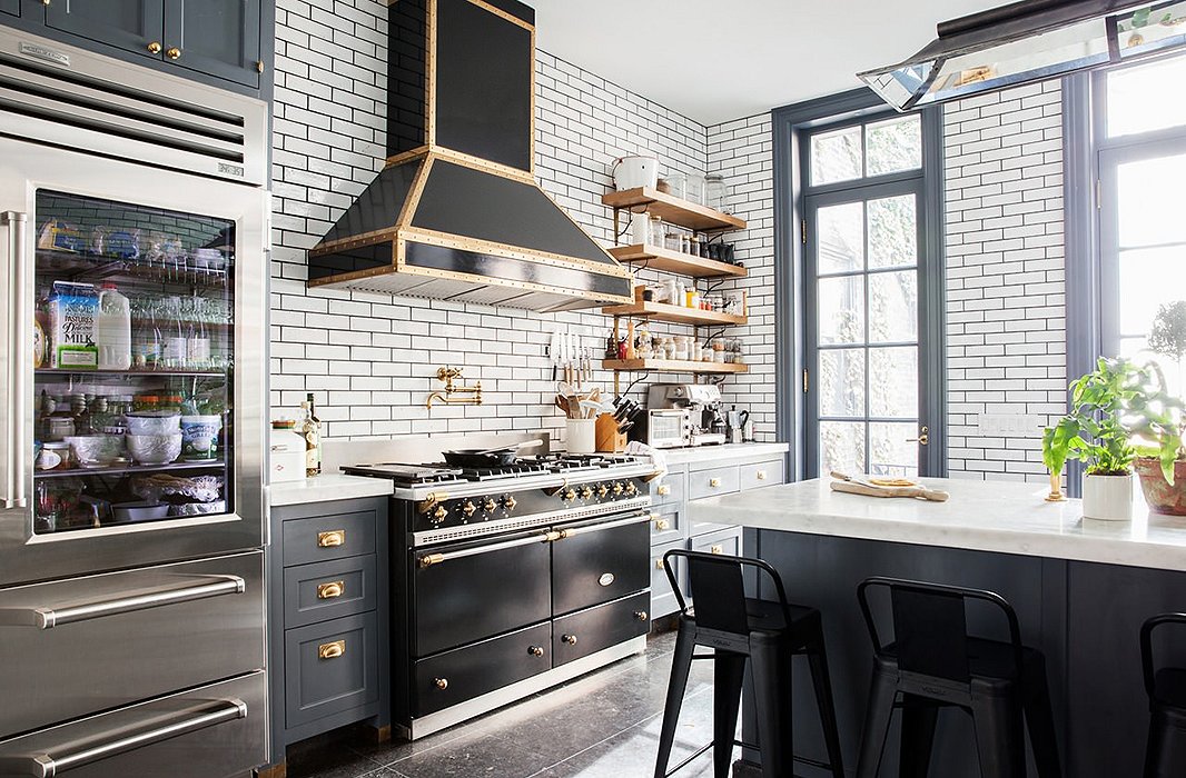 The open wood shelving provides an earthy counterpoint to the Lacanche range, the brass-trimmed hood, and the glass-front refrigerator. Photo by Lesley Unruh.
