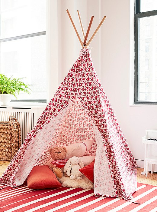 Inside the tepee, a small sheepskin rug and a pile of red-and-white pillows create an extra-soft landing spot.
