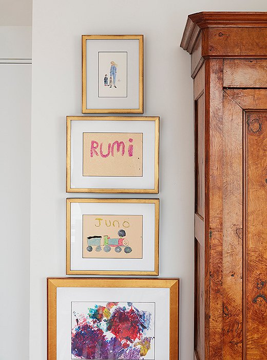 A column of gold frames in varying widths serves as a rotating mini gallery beside the armoire.
