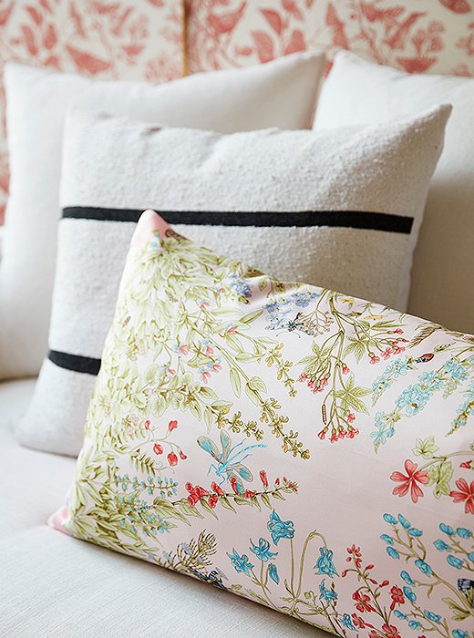 A mix of graphic stripe and floral-print pillows breaks up the room’s red-on-red color scheme—and makes the skirted sofa even cushier.
