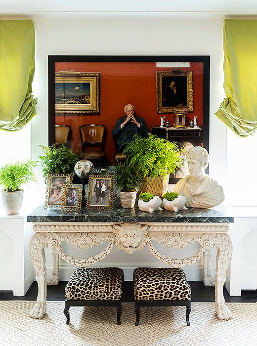 Bridging the gap between the contemporary and the traditional, a pair of leopard-print ottomans rest beneath a George II marble-top console and a Tina Barney photograph. “Sometimes people think he’s part of the family,” Kate says with a laugh of the pensive character framed in black, “and we’re okay with that.”  
