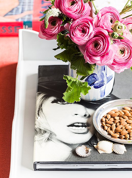 An arrangement of seemingly disparate objects—scattered shells, a book of fashion photographs—comes together on an oversize lacquer tray. Pink ranunculus, one of Kate’s favorite flowers, are a common fixture throughout the apartment.
