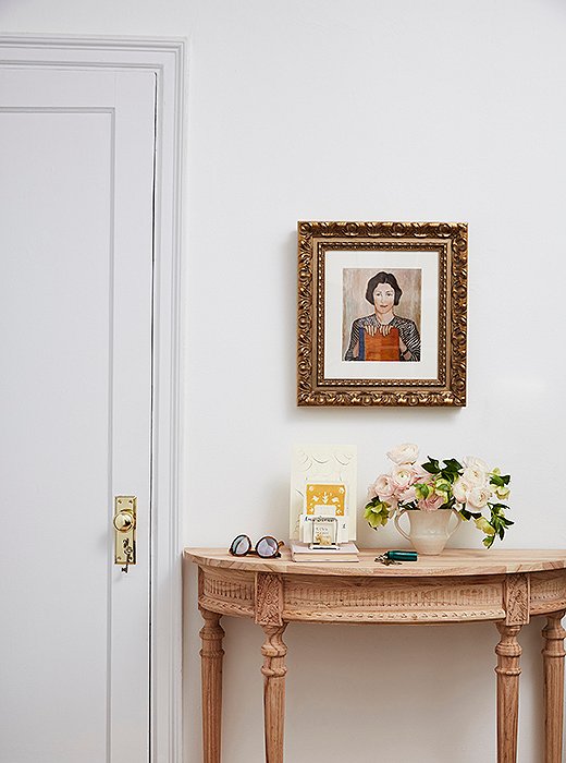 A slim demilune table offers just enough space to drop keys, sunglasses, and mail. “I’ve always loved portraits,” Amy says of the gold-framed artwork above. “It gives the room character and a story.”
