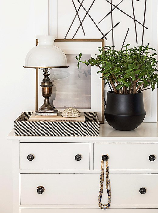 In keeping with the notes of black, a vintage dresser is topped with a painting by Matthew and a favorite photograph taken in Hawaii by husband Zane. The prayer beads are an antique find from Hudson, NY.
