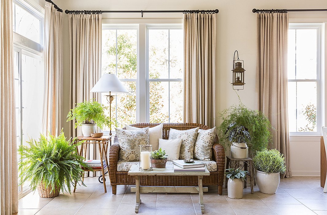 The lush corner lounge area is planted with ferns and other leafy greenery by Matthew’s husband, Zane, an avid gardener. “We have it set up almost to feel like a sunroom with plants,” says Matthew, who upholstered the settee in a pretty floral print and surrounded it with antique tables found locally.
