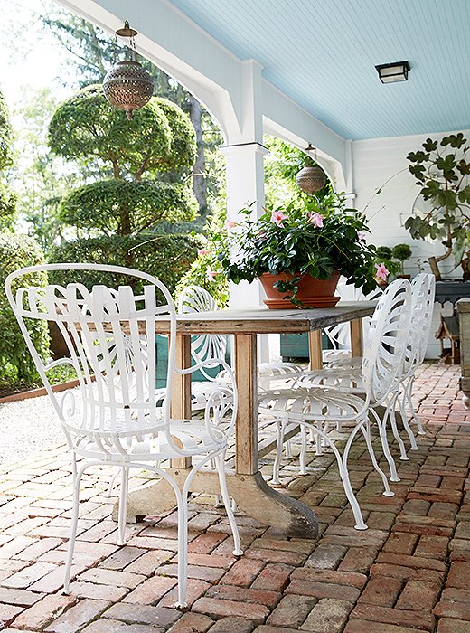 A perfectly shaded spot for Bunny’s summer lunches, the loggia is canopied by a painted-blue ceiling in true Southern style. The metal dining chairs around the wooden trestle table are French.
