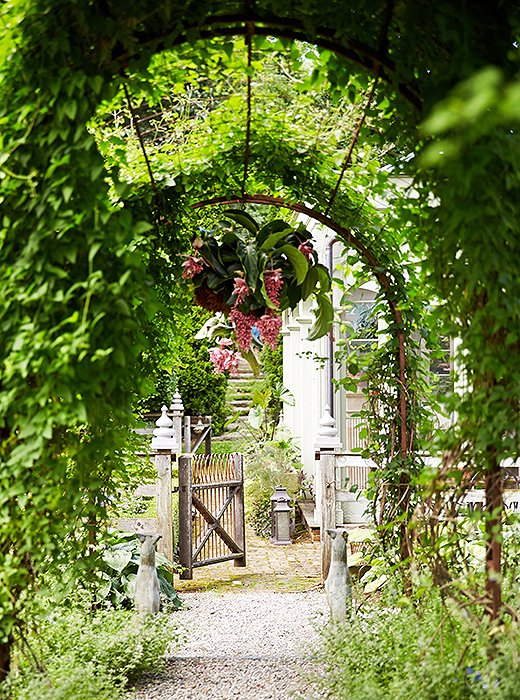 Metal archways entwined with ivy, other vines, and sweet blooms add architectural beauty to the meandering garden paths throughout.
