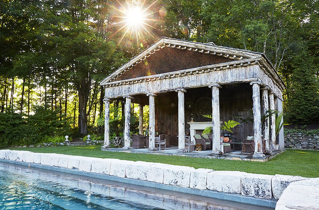 The idea for a colonnaded pool house came from a book on 18th-century garden follies that Bunny discovered in France. Built with salvaged tree trunks, the structure towers over the limestone pool and was made to evoke a classic Greek temple—a nod to all the Greek Revival architecture in Bunny and John’s Connecticut village.
