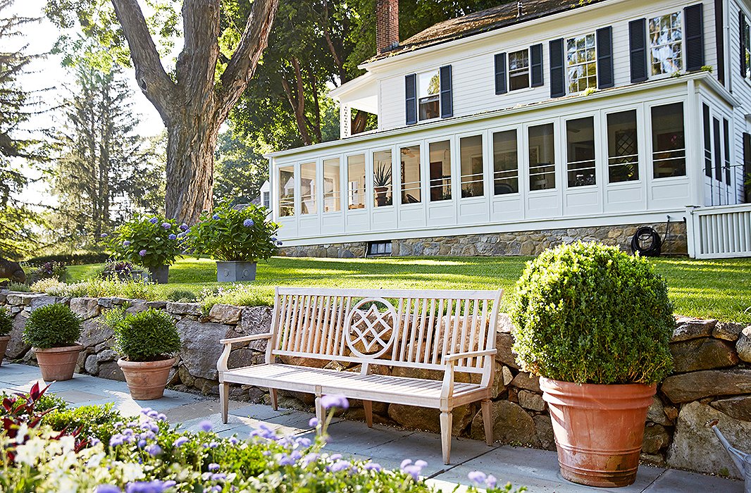 This carved wooden garden bench is one of four that line the walkways framing the sunken garden, which lies just beyond one of the home’s screened-in porches.
