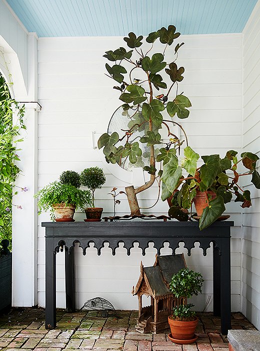 Gothic-style tables bookend the loggia, holding special plants, small topiaries, and vintage garden accents.
