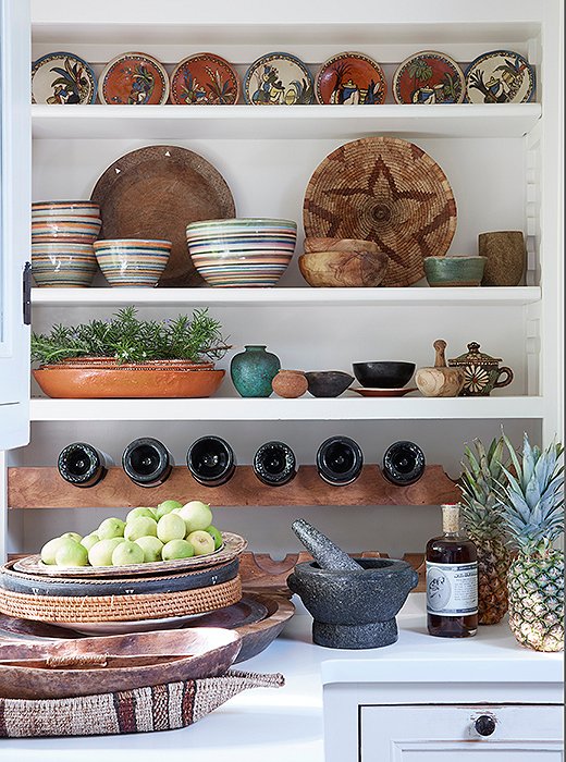 Shelving in the kitchen shows off Kendall’s love of global earthenware. “The pieces are from all over,” says Kendall. “Plates from Mexico, a pre-Columbian pot, trays from Fiji. The rosemary and lemon are from our garden. I eat a lot of pineapple, but I also love the way they look on a counter.”
