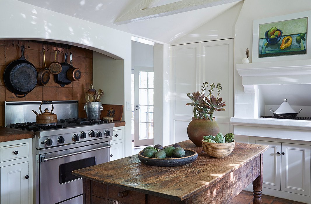 This kitchen is not just for show. “That stove is constantly in use,” says Kendall. “And our table is always full of fresh produce from our garden.” A silver ice bucket corrals wooden spoons beneath iron and copper pots. A painting by Kendall’s sister, Cayetana hangs above a traditional tagine.
