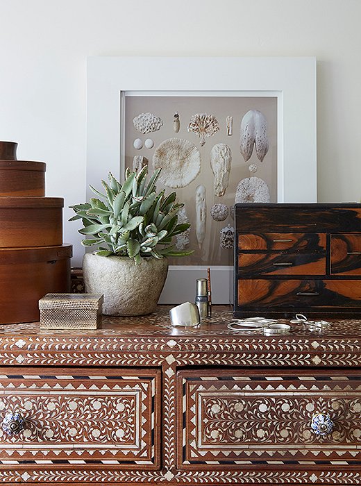 An array of textures tops the Indian inlaid bureau in the master bath. “The little snakeskin box and a tigerwood set of drawers hold my jewelry,” says Kendall. “The photo is by my friend Charles Fine, an L.A. artist. His pictures of nature really inspire me.”
