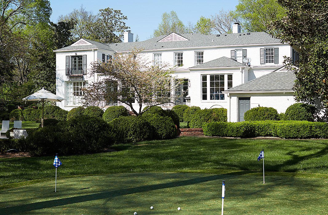 The lawn of the 1942 house has much of its original plantings and trees, but the couple added a little putting green near the pool.
