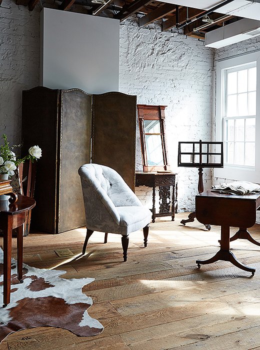 Old and new live in seamless harmony on the boutique’s second floor, where a four-panel embossed-leather folding screen and a 19th-century drop-leaf table join a chair designed by Darryl and upholstered in a reversed toile.
