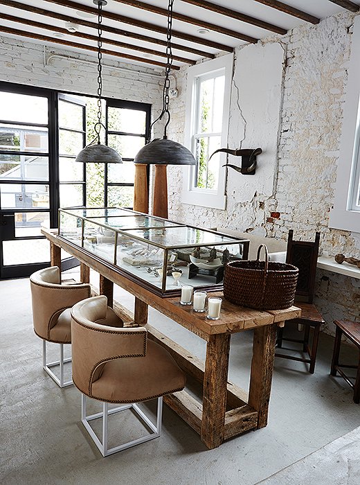 For the first-floor “kitchen” in the boutique, Darryl topped an old farm table with an antique apothecary case for his unique objets. The Shaw pendants (“named for the neighborhood in which we sit”) are by Darryl for Urban Electric Co., and he refurbished the midcentury office chairs with metal bases and kidskin leather.
