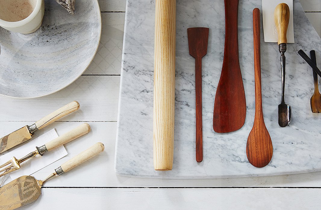 Handmade ceramics, a marble prep board, and new and vintage serving and cooking utensils are housed in an antique apothecary case.
