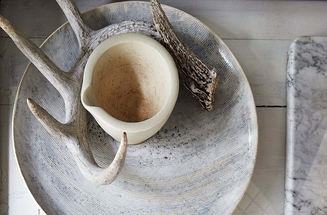 Darryl worked with local ceramicist Ani Kasten to design the white-glazed charger with a thumbprint motif. Atop are an elk antler and a vintage stone soap dish.
