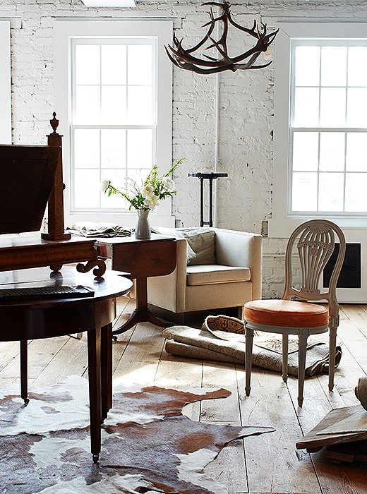 Timeless designs, including American antiques (“A piece is timeless when it has appropriate scale and clean lines—American antiques are very clean-lined”) and upholstered pieces by Darryl, are mixed in with antique rugs, hides, and an antler chandelier.
