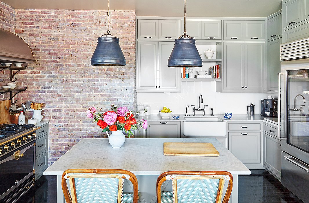 The designer had the bistro-style barstools custom-made by TK Collections to match the cabinetry; find similar options here. She echoed the industrial feel of brick in a pair of weathered zinc pendants over the island.
 
