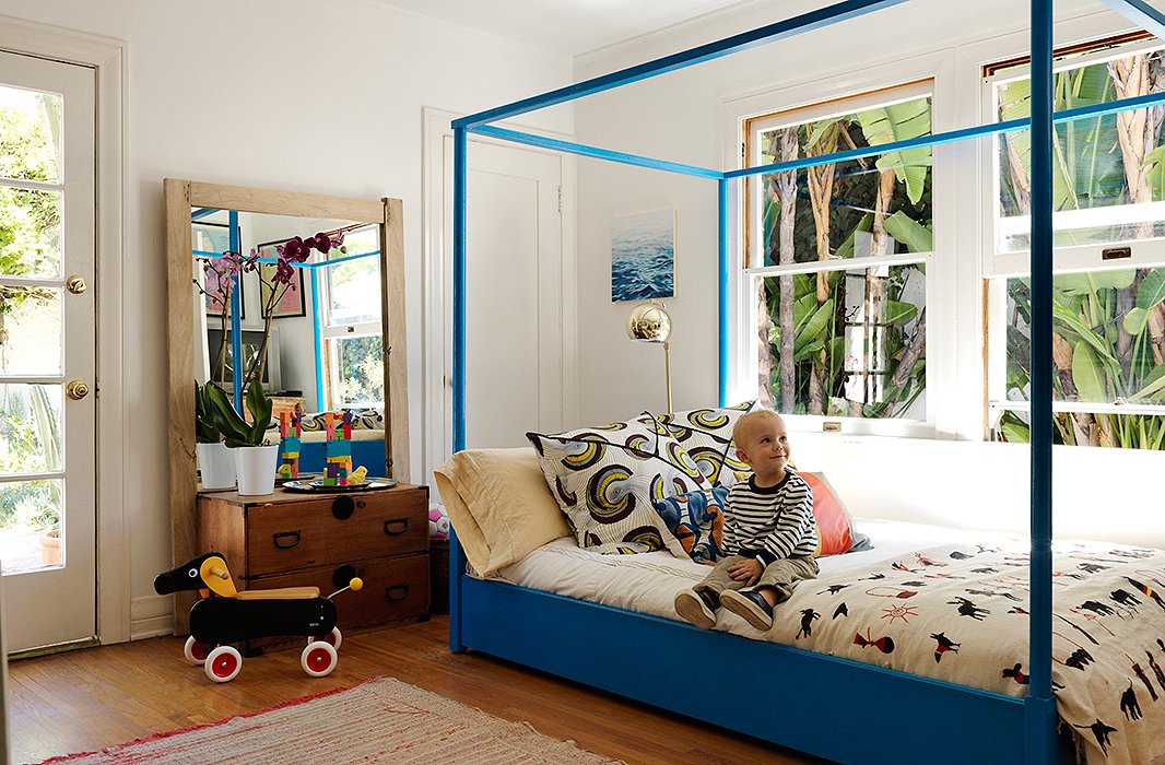 Son Alfie sits on a four-poster bed in its latest incarnation. “It used to be a guest bed, so we just cut off the legs,” says Heidi. “It has been at least six colors; I call this shade ‘shaping room blue’—it’s the color of my dad’s shaping room.” The throw was found at the Echo Park Craft Fair, and the chest used to house tools in the garage.
