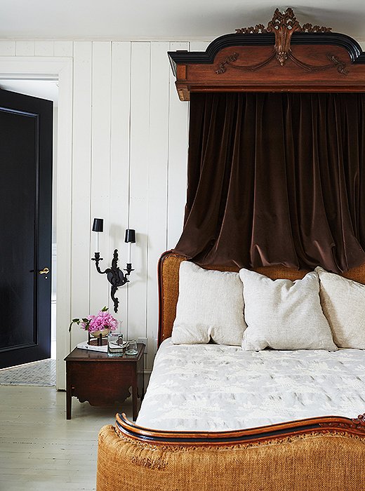 Darryl chose this guest bed for its burlap upholstery and articulated frame, which he embellished with black paint. The canopy—likely the former top of an armoire, he notes—is draped with velvet fabric. “I am generally not a fan of a canopy,” he says. “But I felt it completed the space.”
