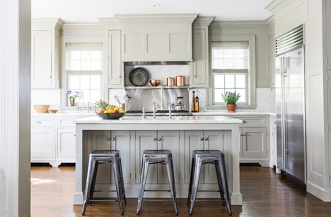 Painted a Farrow & Ball green, the kitchen features a Sub-Zero refrigerator, a Wolf range, Perrin & Rowe sink fittings, and marble countertops and backsplash.
