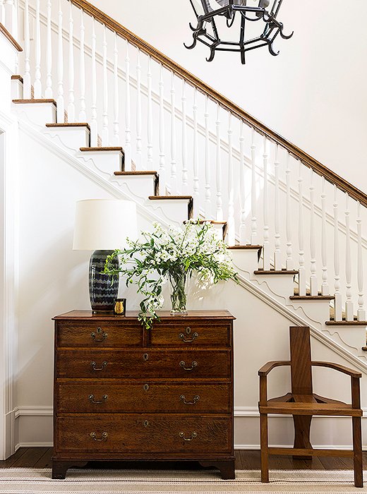 An antique dresser, a contemporary Craftsman-inspired chair, and a glamorous painted table lamp in the foyer set the tone for Brett’s home with a mix of old and new items.
