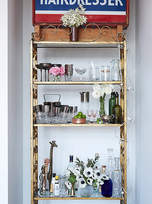 Rosie and Ambi, both big entertainers, found a perfect recessed corner in the living room for a salvaged étagère that holds their collection of vintage glassware and barware.
