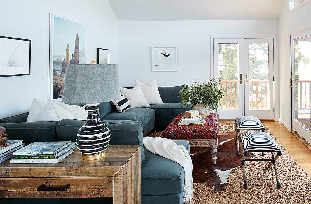 The family room of this lake house puts the focus on the view instead of on a TV screen (though there’s a place for that too). An upholstered ottoman in place of a coffee table offers extra space to kick up your feet. In front of the ottoman are two striped Jean stools for extra flexibility. Find a similar hide rug here. Photo by Mark Weinberg; design by One Kings Lane Interior Design.
