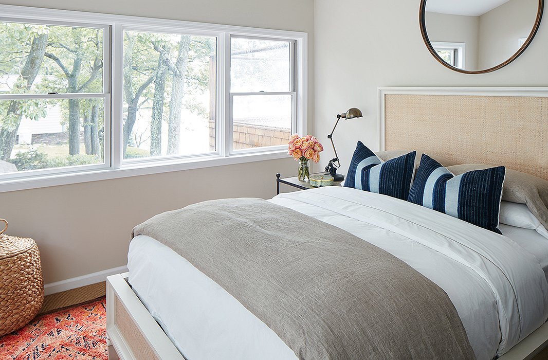 Simple side tables and lighting and neutral linens give this guest room an open, tranquil feel. A vintage rug brings in color; a large mirror (similar to this one) draws the eye up.
