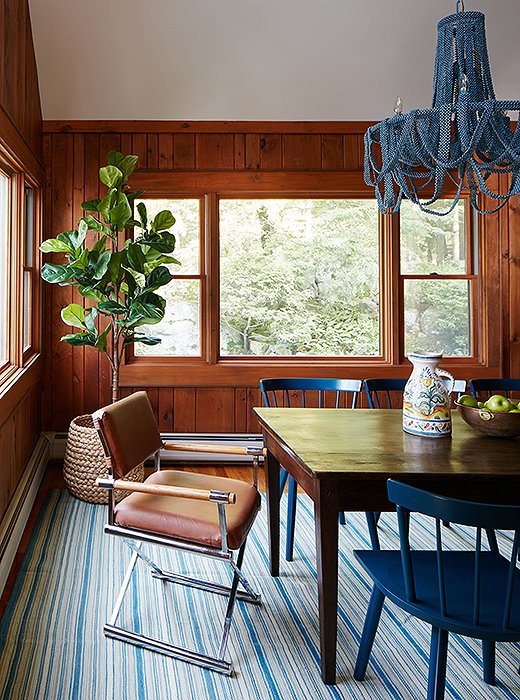 The beaded chandelier and the vintage rug pair perfectly with the blue dining chairs. The wood paneling was left unpainted to add traditional warmth to the room.
