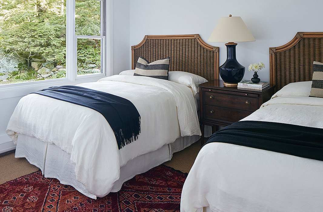 In the other twin guest room, bamboo beds and a vintage rug create a sophisticated but still relaxed retreat. The deep-blue throws and table lamp keep the room cohesive with the rest of the house.
