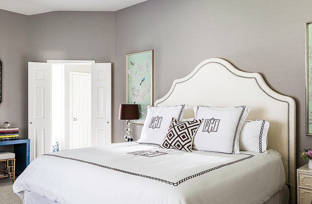 The master bedroom is one of Paloma’s favorite spaces. “It is kind of a departure from the rest of the home,” she says. “It’s much more feminine and glamorous.” Adding to the drama are a sumptuous upholstered headboard, monogrammed linens, and silk wall panels on both sides of the bed.
